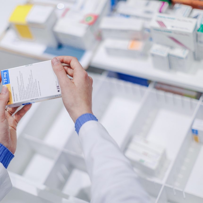 Close-up of pharmacist holding medicines in a pharmacy.